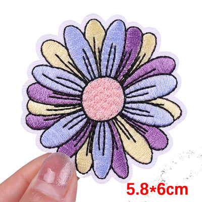 Colorful flower-shaped patch held by a hand with dimensions indicated.