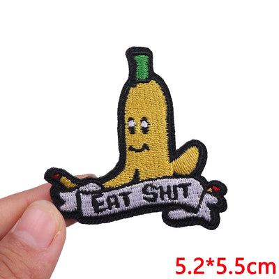 Banana-shaped patch with 'EAT SHIT' text held by a hand on a white background