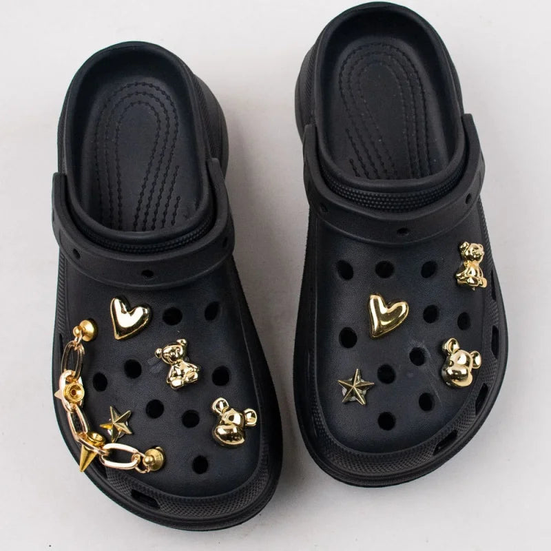 Black clogs with gold embellishments on a white background