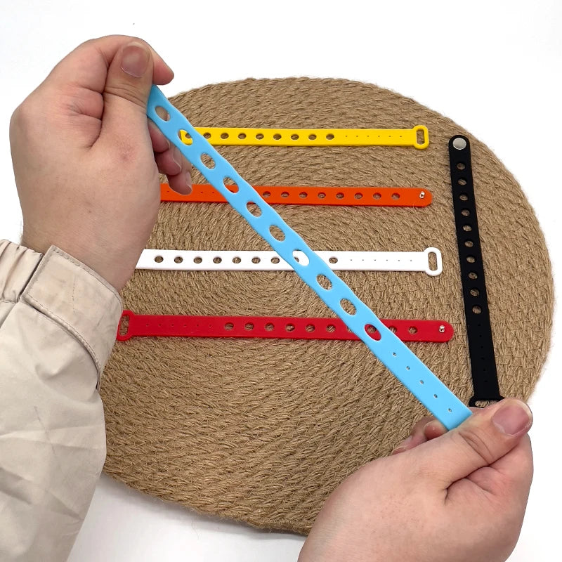 Colorful wrist bands on a textured surface with a hand holding one ruler.