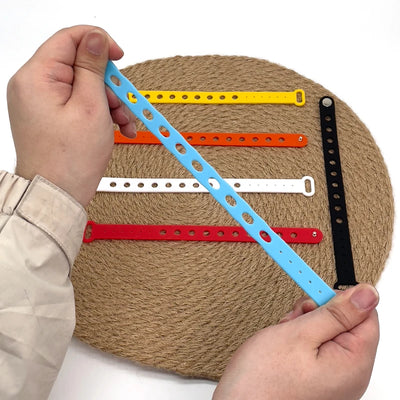 Colorful wrist bands on a textured surface with a hand holding one ruler.