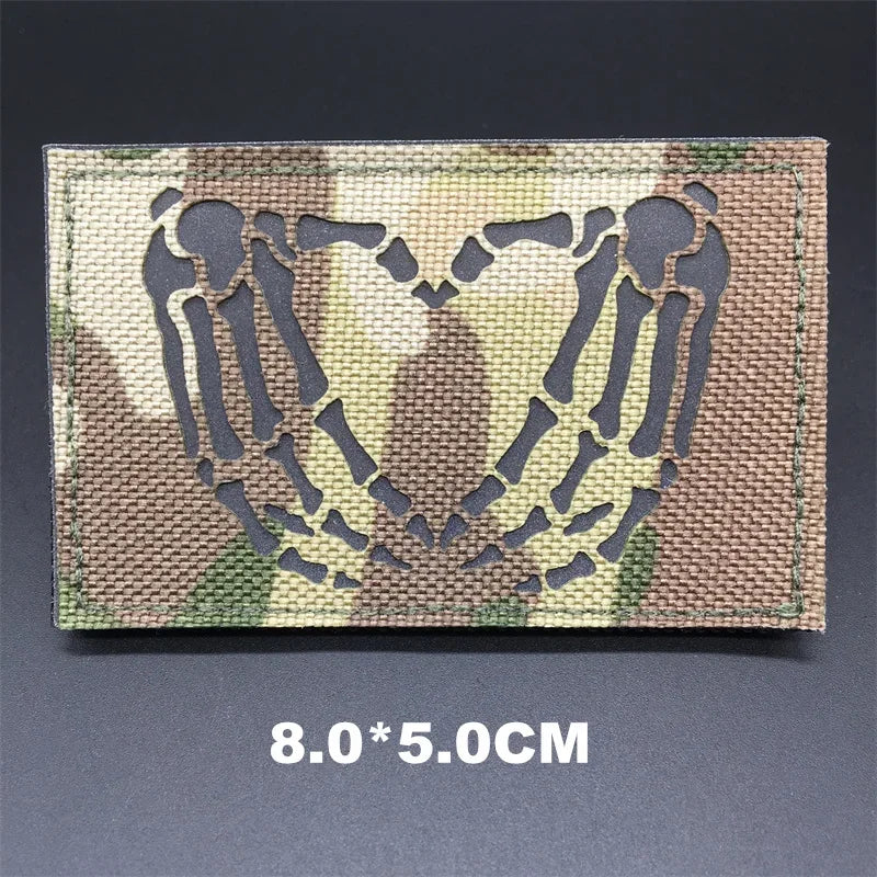 Camouflage patch with skeleton hands forming a heart on a dark background
