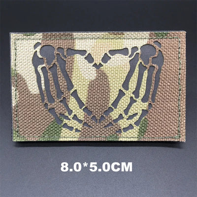 Camouflage patch with skeleton hands forming a heart on a dark background