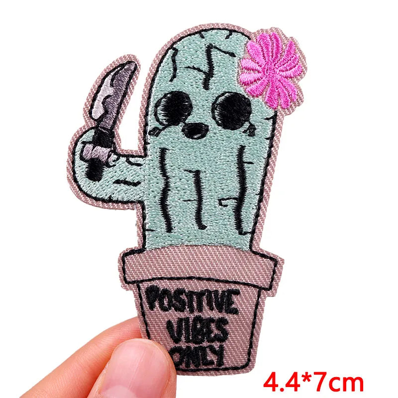 Embroidered patch of a cactus with sunglasses and a flower, labeled 'Positive Vibes Only', held by a hand.