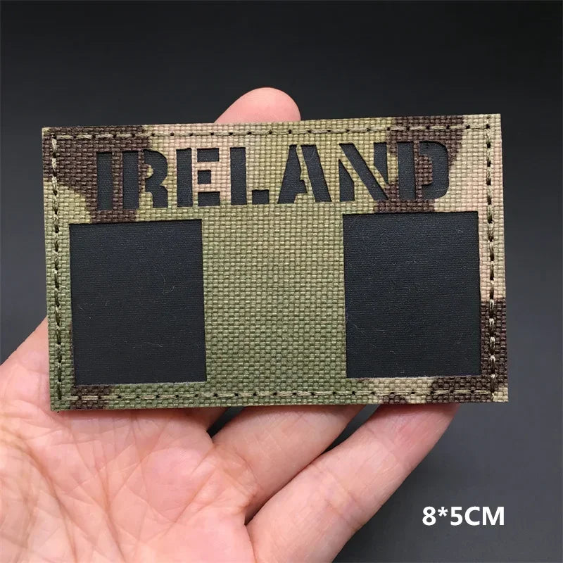 Ireland flag camouflage patch held in a hand against a dark background. g 