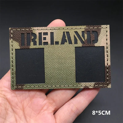 Ireland flag camouflage patch held in a hand against a dark background. g 