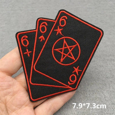 Two black patches with red symbols held by a hand on a gray background