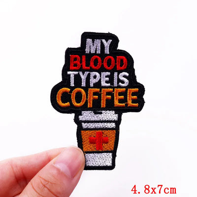 Patch with 'My Blood Type is Coffee' text held by a hand on a white background