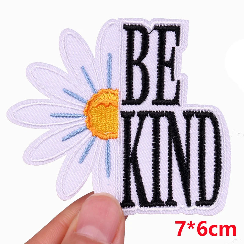 Patch with daisy flower and 'BE KIND' text held by a hand, size 7*6cm.