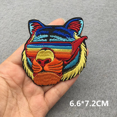 Colorful embroidered patch of a cat's face held in a hand on a gray background