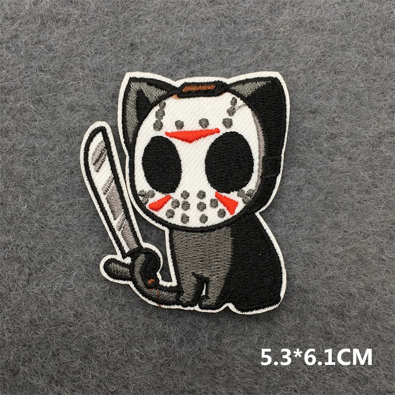 Embroidered patch of a black cat with a skull face holding a baseball bat on a gray background.