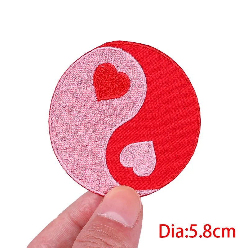 Circular patch with red and pink design held by a hand on a white background