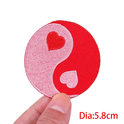 Circular patch with red and pink design held by a hand on a white background