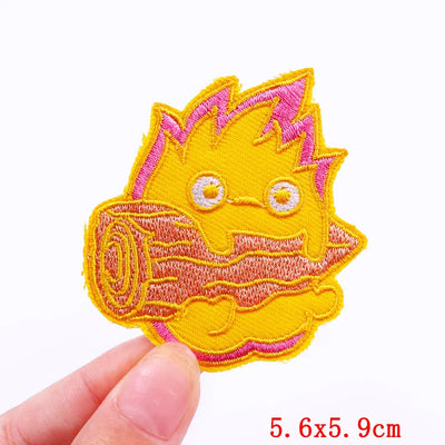 Embroidered patch with a cartoonish design held by a hand on a white background