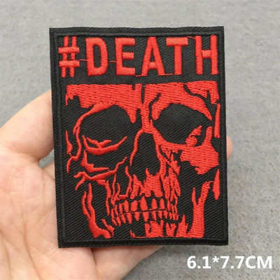Embroidered patch with red skull design and '#DEATH' text held in a hand on a gray background.