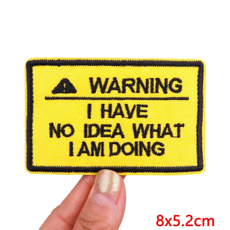Yellow patch with black text 'WARNING I HAVE NO IDEA WHAT I AM DOING' held by a hand on a white background.
