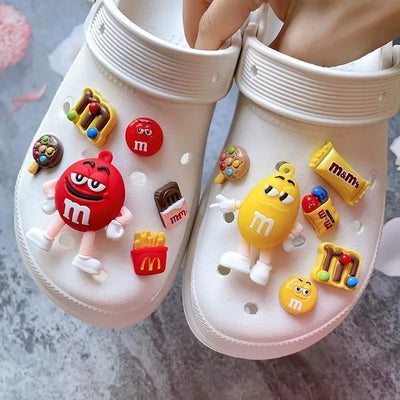 White shoes with colorful M&M-themed charms on a gray surface