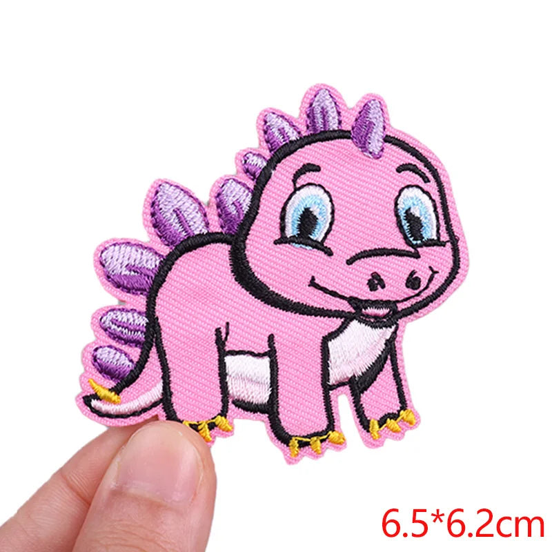 Pink cartoon dinosaur patch held by a hand with size label &