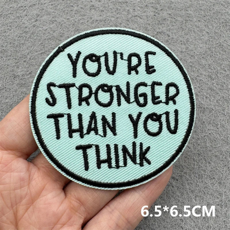 Motivational patch with text 'You're Stronger Than You Think' held in a hand against a gray background.