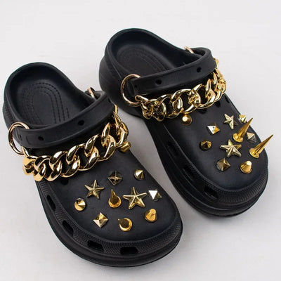Black clogs with gold chains and studs on a white background