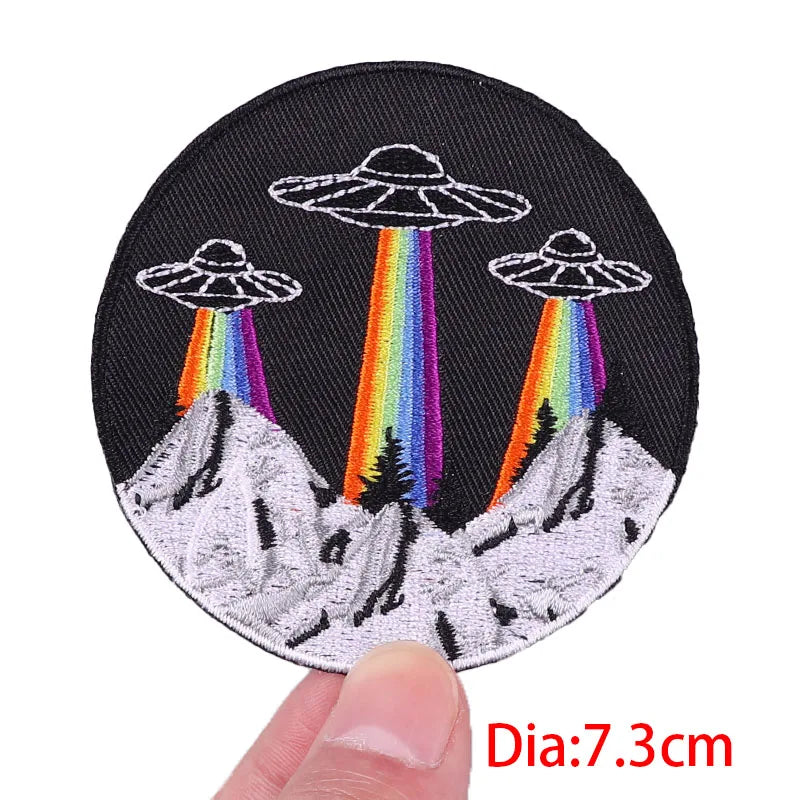 Circular patch with UFOs and rainbows held by a hand, labeled 'Dia:7.3cm'.