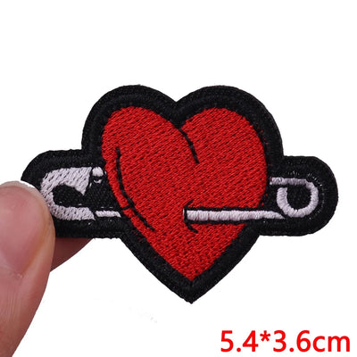 Heart-shaped patch with a safety pin held by a hand on a white background
