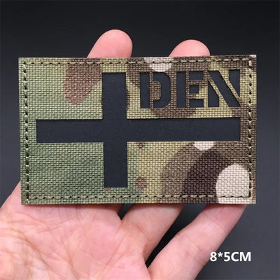Denmark flag Camouflage patch  held in a hand against a dark background