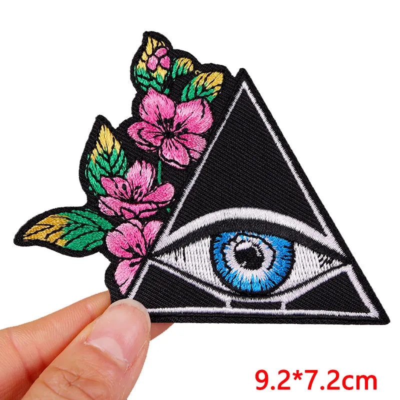 Embroidered patch with eye and floral design held by a hand, size 9.2*7.2cm.