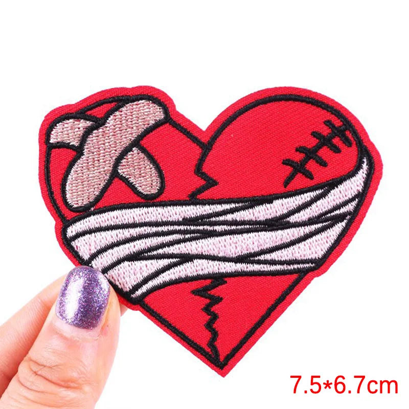 Heart-shaped patch with a bandage design held by a hand on a white background