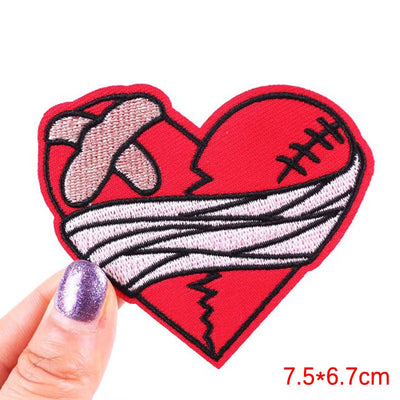 Heart-shaped patch with a bandage design held by a hand on a white background