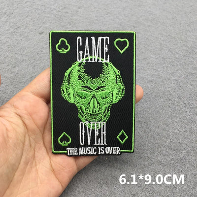 Embroidered patch with skull design and text held in a hand on a gray background