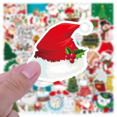 Hand holding a Christmas-themed sticker with a Santa hat and holly berries against a colorful blurred background.