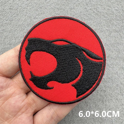 Red and black circular patch held in a hand on a gray background