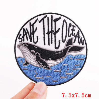 Round patch with whale and 'Save the Ocean' text held by a hand on a white background