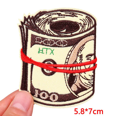 Embroidered patch of a dollar bill roll with a red rubber band, held by a hand.