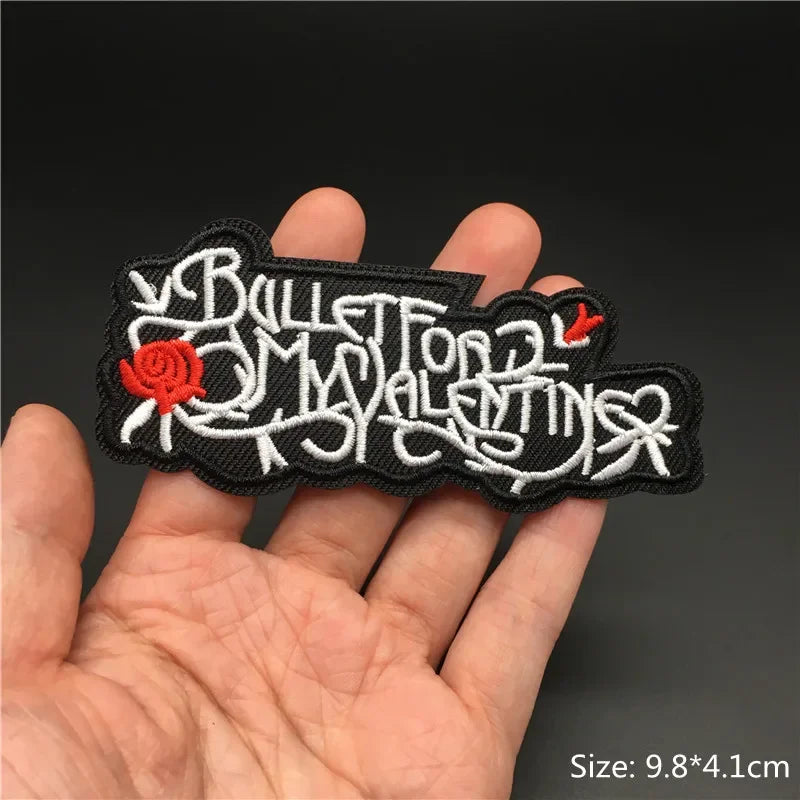 Hand holding a black white and red Bullet For My Valentine embroidered iron-on patch 9.8x4.1cm on a dark background