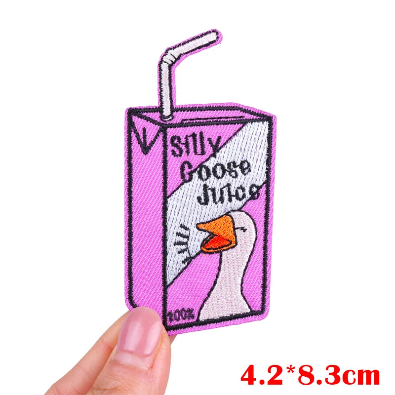 Patch of a pink juice box with a duck and 'Silly Goose Juice' text, held by a hand.