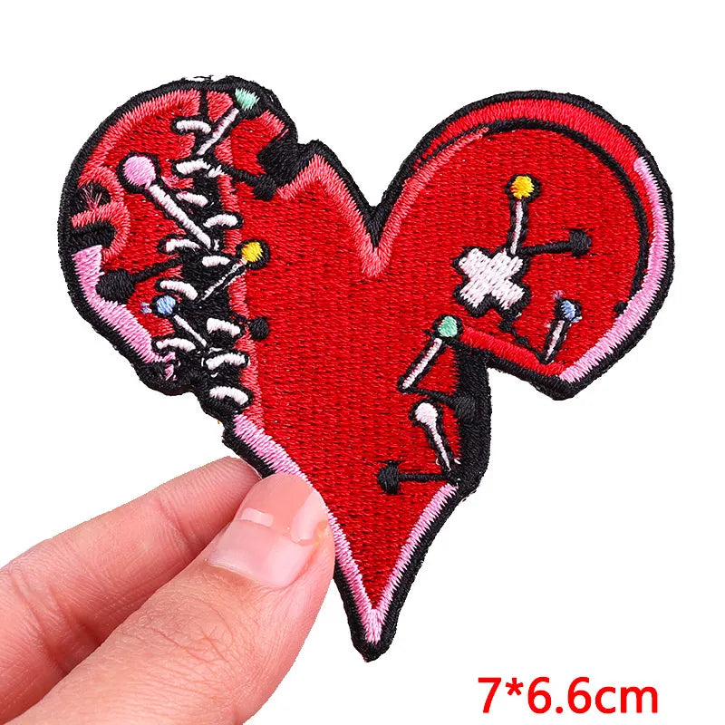Heart-shaped patch with skeleton design held by a hand, on a white background