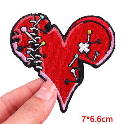 Heart-shaped patch with skeleton design held by a hand, on a white background