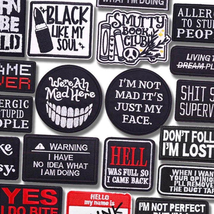 Collection of various black and white patches with text designs on a white background