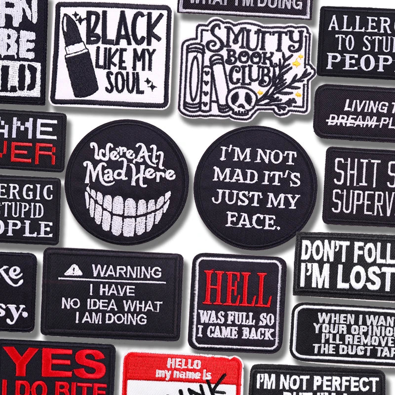 Collection of various black and white patches with text designs on a white background