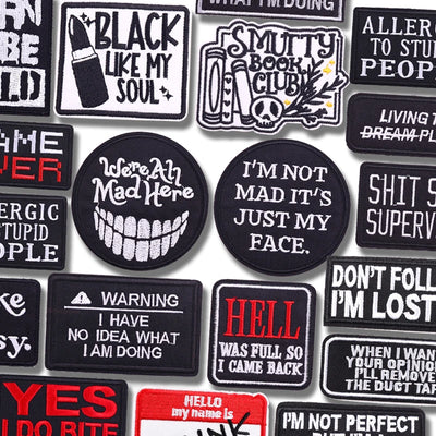 Collection of various black and white patches with text designs on a white background