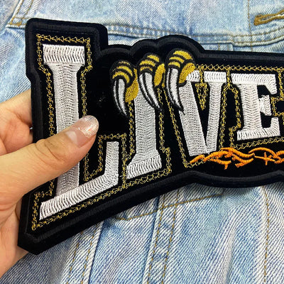 Patch with 'LIVE' text held over a denim background