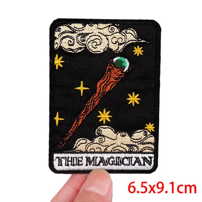Embroidered patch of 'The Magician' from tarot cards held by a hand, with dimensions displayed.