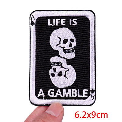 Patch with skull design and 'Life is a Gamble' text held by a hand, with dimensions displayed.