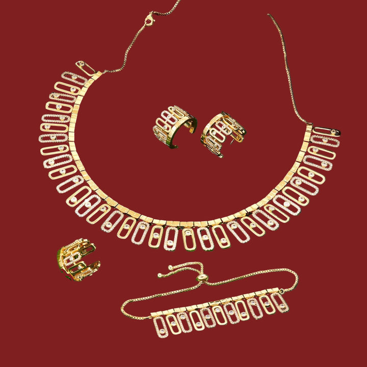 Gold necklace, earrings, ring and bracelet set on a red surface 