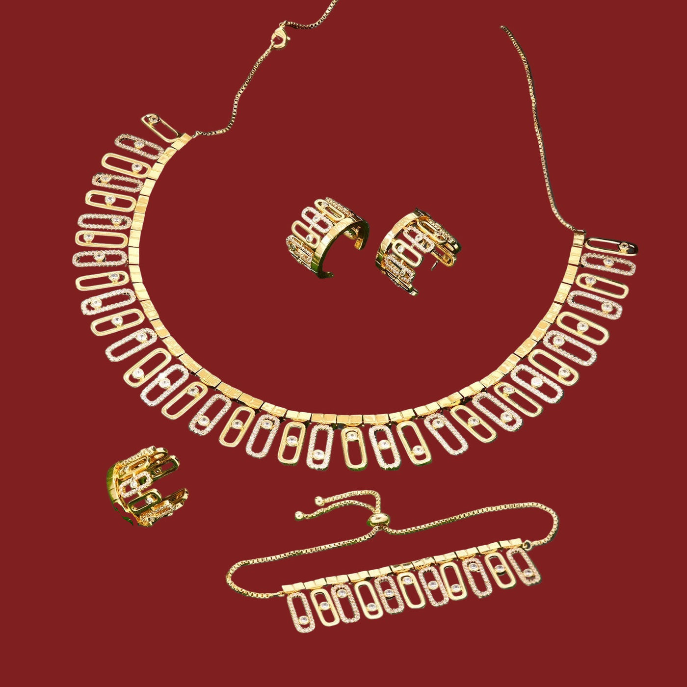 Gold necklace, earrings, ring and bracelet set on a red surface 