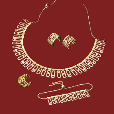 Gold necklace, earrings, ring and bracelet set on a red surface 