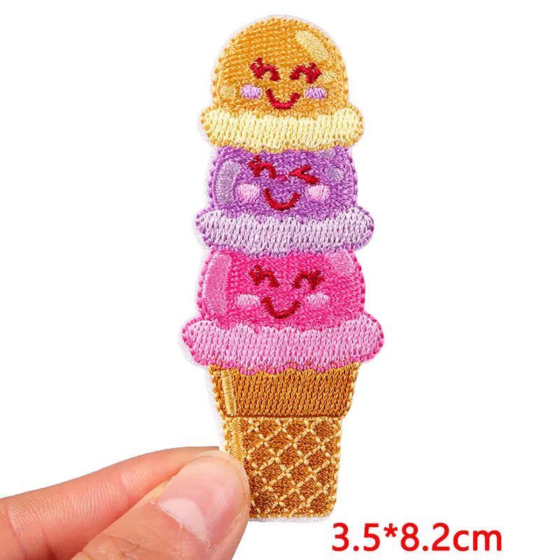 Embroidered ice cream cone patch with smiling faces held by a hand on a white background