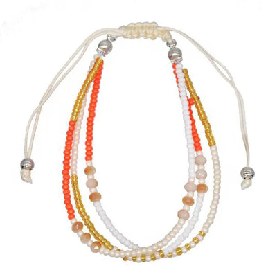 Multistrand beaded necklace with white, orange, and gold beads on a white background